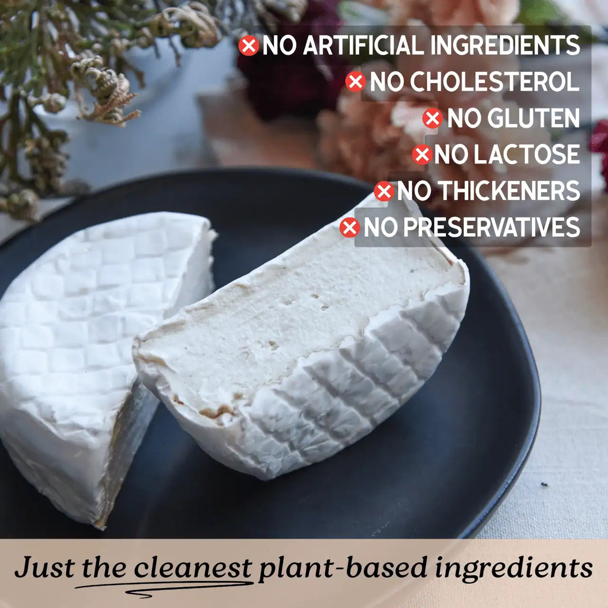 A wedge and half of soft white plant-based Brie cheese on a dark plate, with text overlays highlighting clean ingredients and a bottom banner reading 'Just the cleanest plant-based ingredients.'.