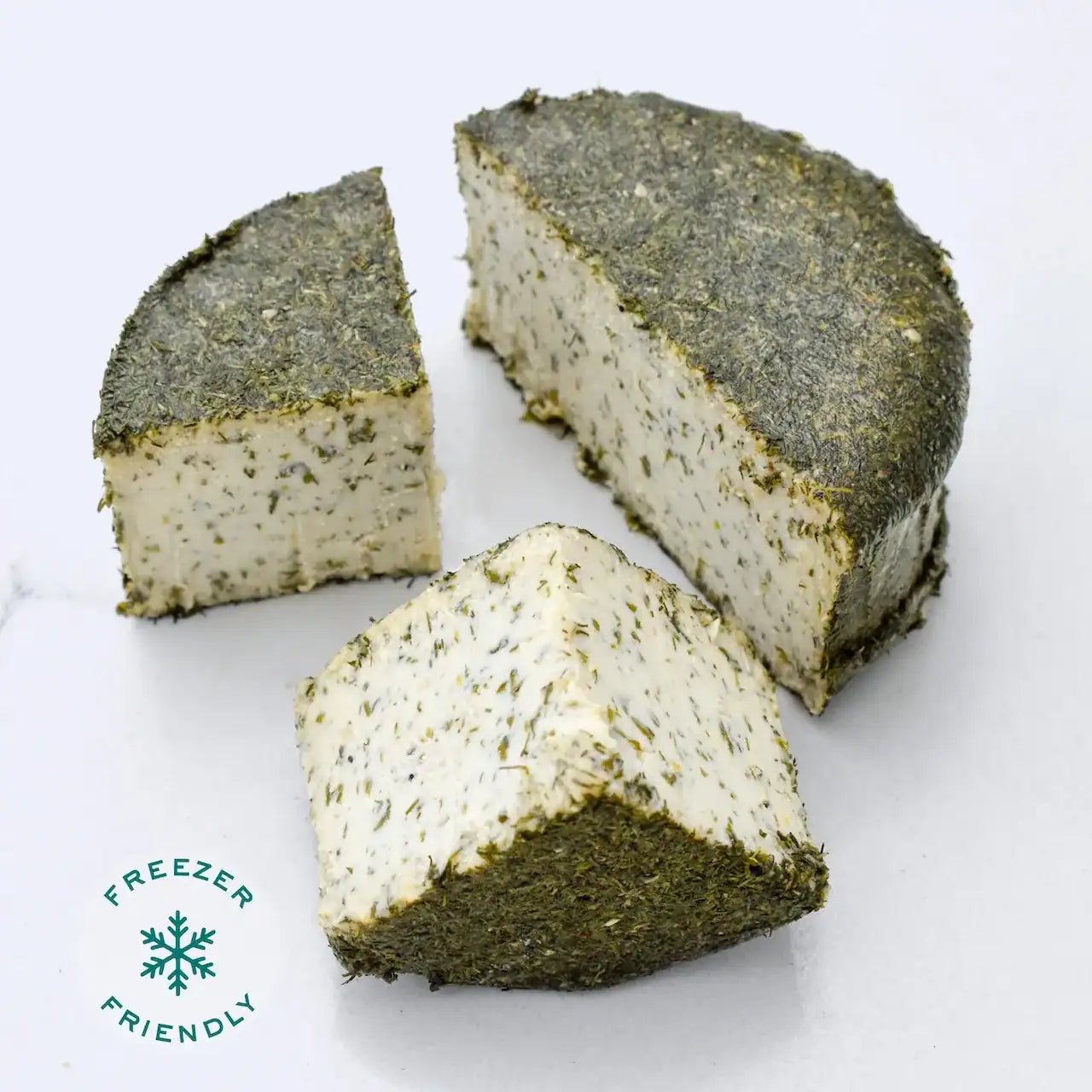 Slices of dairy-free Lemon Dill Fromage on a white marble background