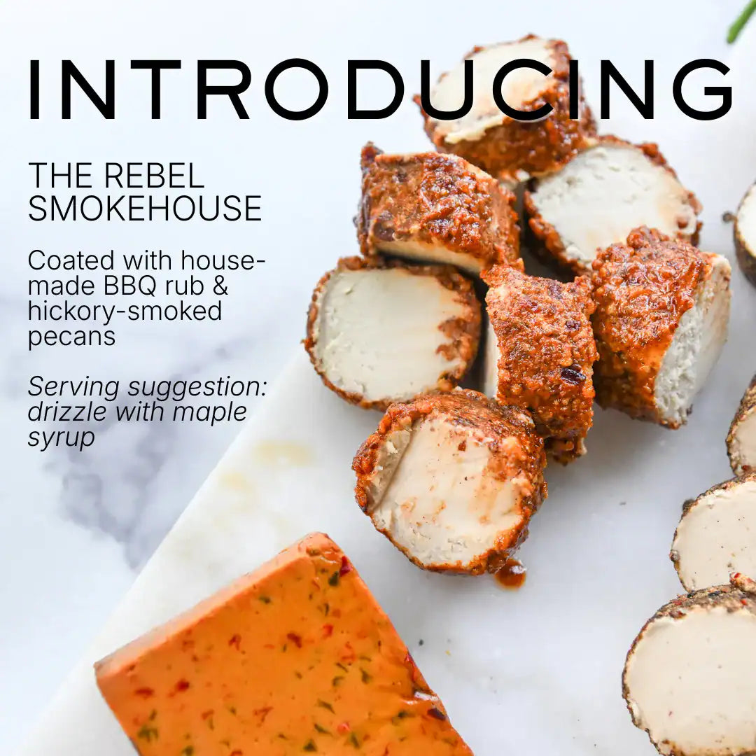 Brand new Rebel Cheese Smokehouse Pecan Chevre dairy-free cheese made with in-house BBQ rub and hickory-smoked pecans on a marble surface.