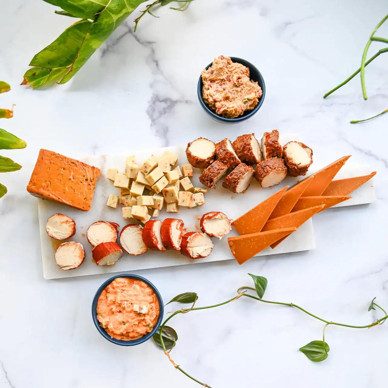 Platter of assorted dairy-free cheese snacks on a marble surface.