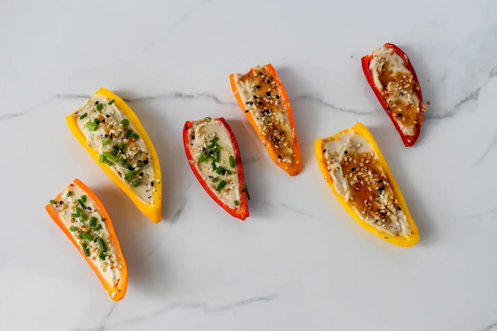 Colorful bell pepper boats filled with a mixture on a white marble surface