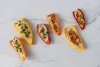 Colorful bell pepper boats filled with a mixture on a white marble surface