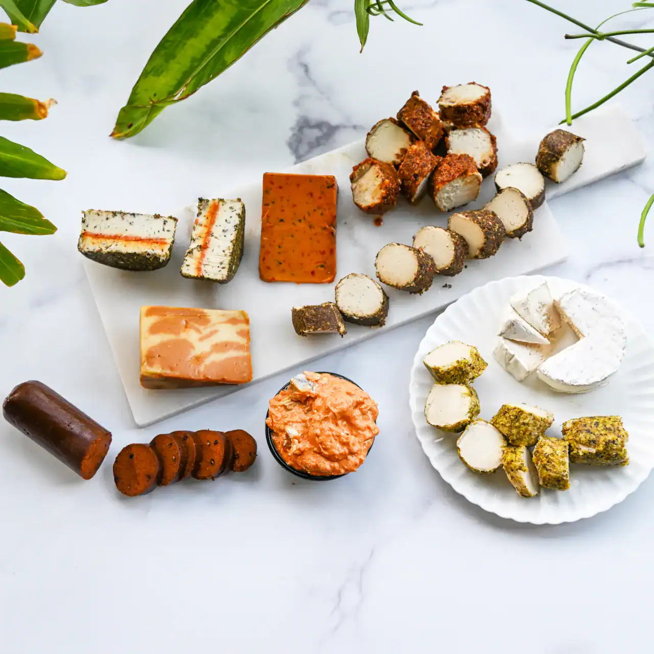assorted dairy-free cheeses and vegan salami on a cheese board on a marble background