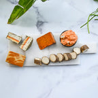 Assorted dairy-free cheeses on a marble surface with green leaves.