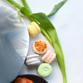 Five vegan macarons of different colors on a white background