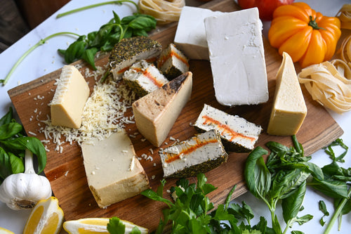 Assorted cheeses on a wooden board with herbs and vegetables