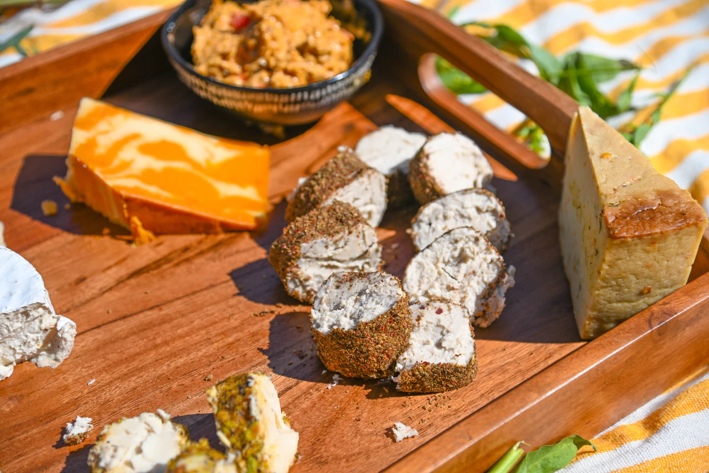 Wooden board with Rebel Cheese Triple Peppercorn Chevre and various types of cheese.
