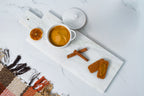 Plant-based Pumpkin Spice Cream Cheese in a white crock with cinnamon sticks and spiced cookies on a marble board.