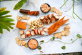 Assorted dairy-free cheese, dips, crackers, and vegan salami on a marble surface with green leaves.