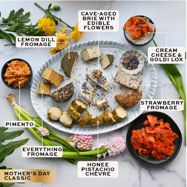 Assorted food items including brie, crackers, olives, and other snacks on a white surface with labels.